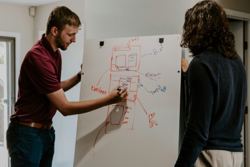 Man drawing a complex diagram on a dry-erase board
