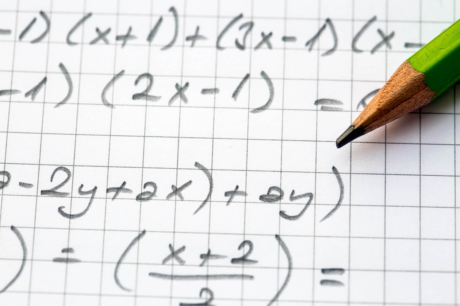 Pencil resting on a paper with several math equations written on it